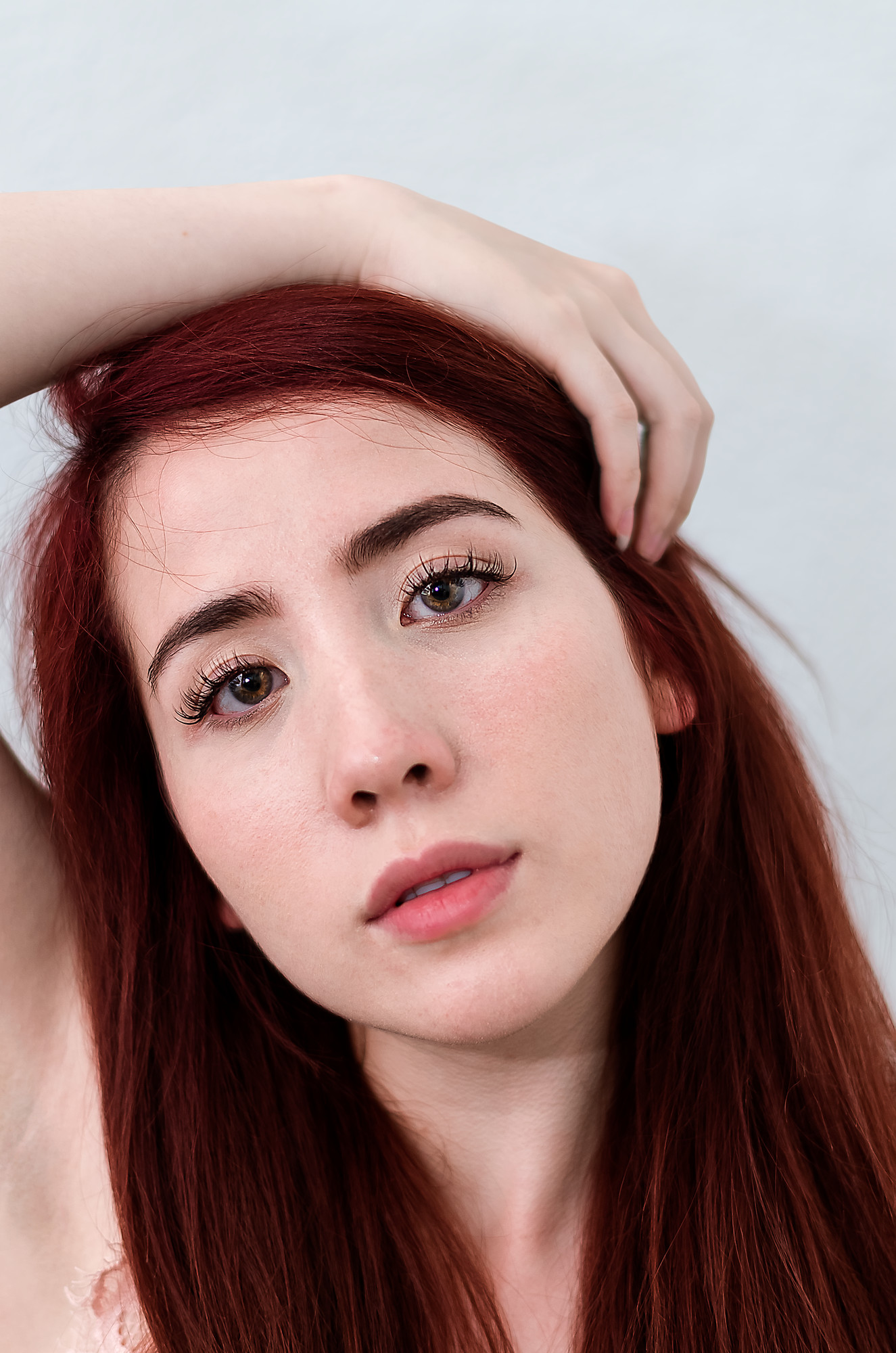 High-key beauty portrait after retouching, pores and freckles intact, brows and lashes defined